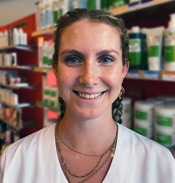 Eine Frau mit geflochtenen Zöpfen und Goldschmuck lächelt in der Laurentius-Apotheke in Imst / Arzl im Pitztal.