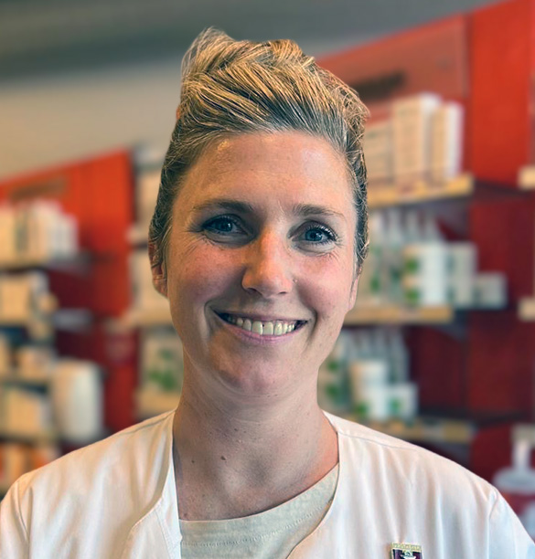 Eine Frau in einem weißen Laborkittel lächelt in die Kamera in der Laurentius Apotheke Imst / Arzl im Pitztal.